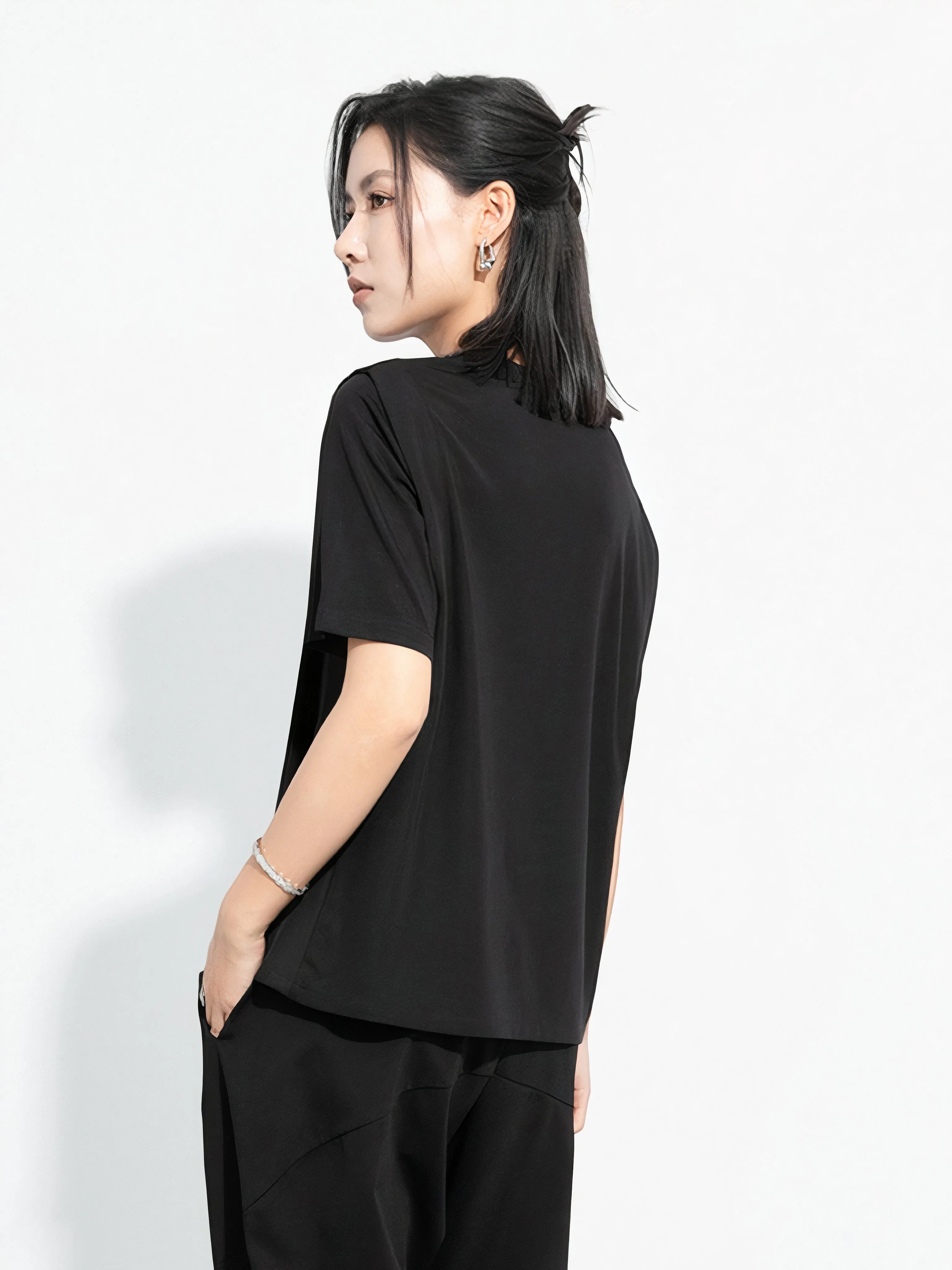 Black minimalist Japandi-style top worn by a woman, asymmetrical design and oversized fit, product by Sumoka Studio.